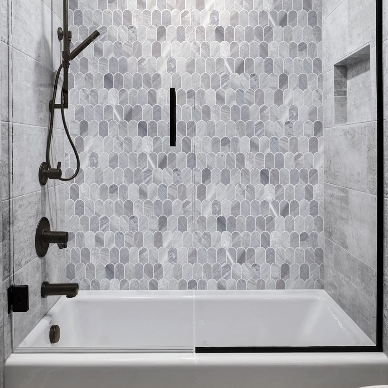 white bathtub with black accessories and gray small tile wall pieces from Traditional Floors in Milan, IL